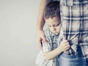 a little boy hugging his father to stay