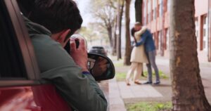 Private investigator secretly photographing a couple, illustrating legal risks of secretly recording a spouse in North Carolina.