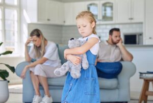 Sad child holding a teddy bear while parents argue during a custody dispute in Raleigh, NC